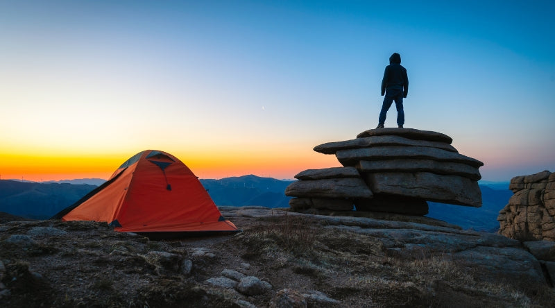 Un homme et sa tente au sommet d'un cap rocheux qui regarde un coucher de soleil - Collection meilleurs vendeurs Koksoak Outdoor