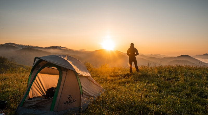 Campeur avec Tente 1 place regardant le coucher de soleil