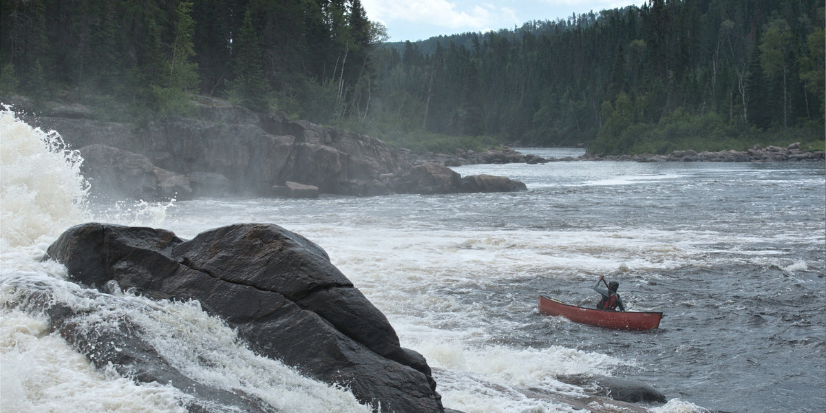 Canot solo en eau vive au bas des chutes Chaudière sur la rivière Ashuapmushuan avec forêt en arrière plan
