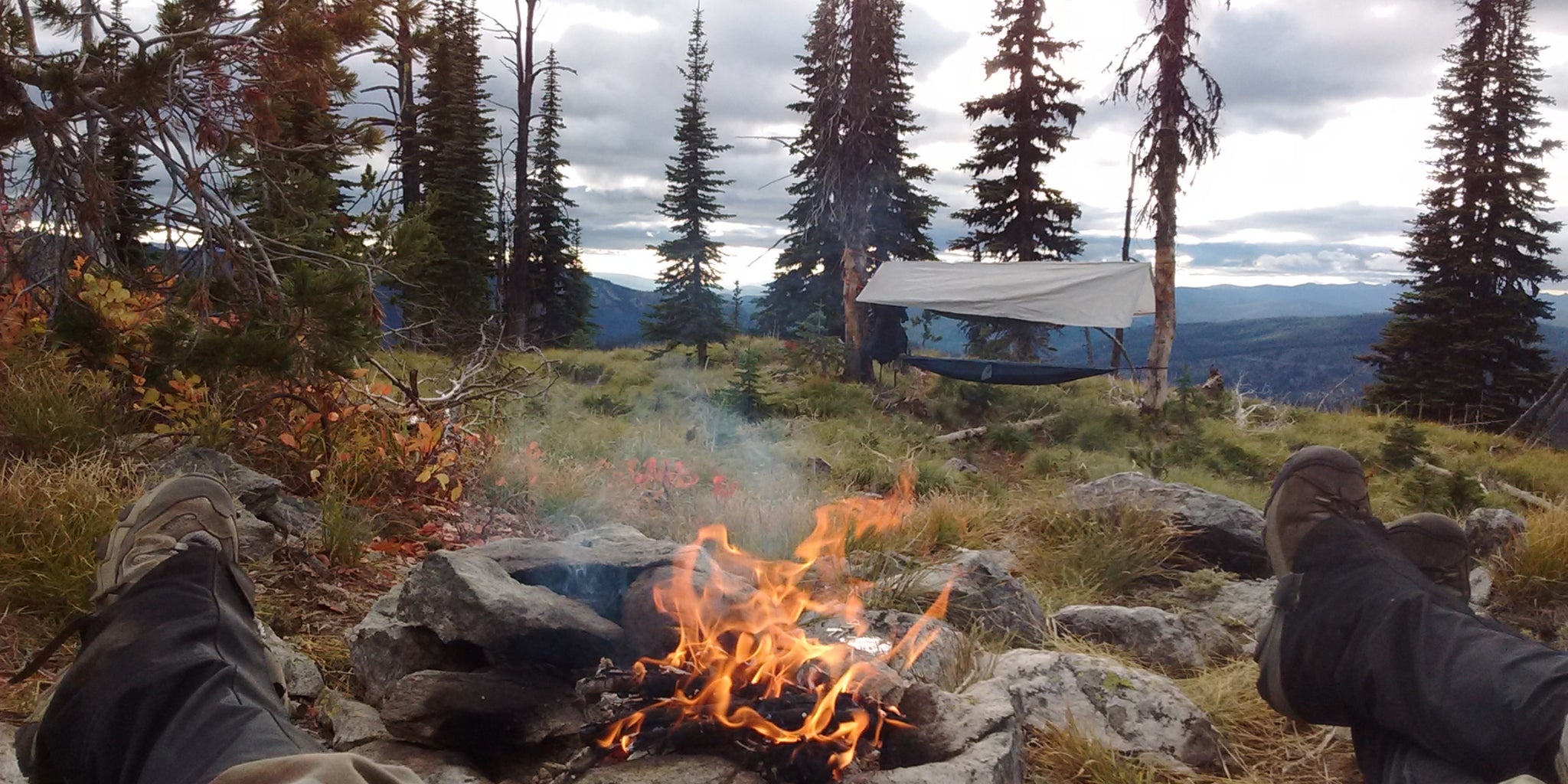 Tente tarp et hamac en forêt - 2 randonneurs près d'un feu de camp en montagne