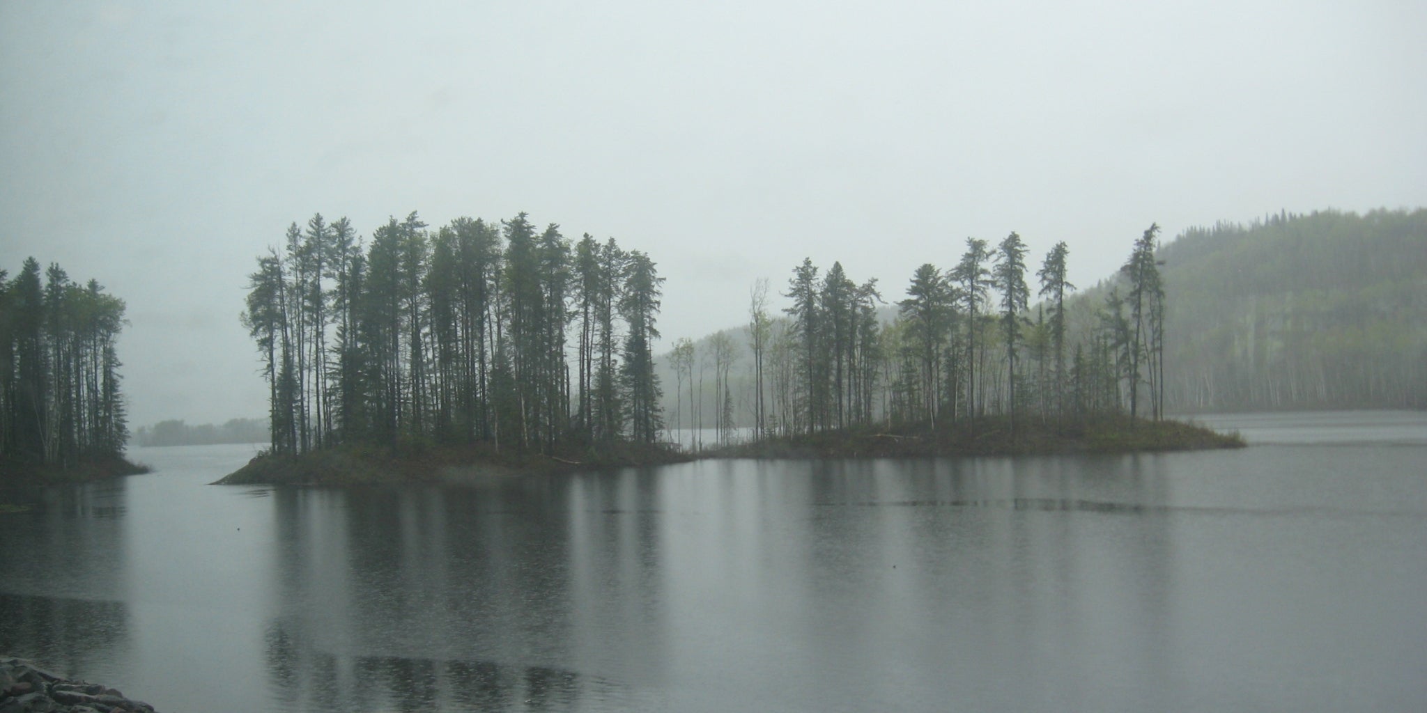 Deux îlots d'arbre au milieu d'un lac sous la pluie qui tombe - Koksoak Outdoor