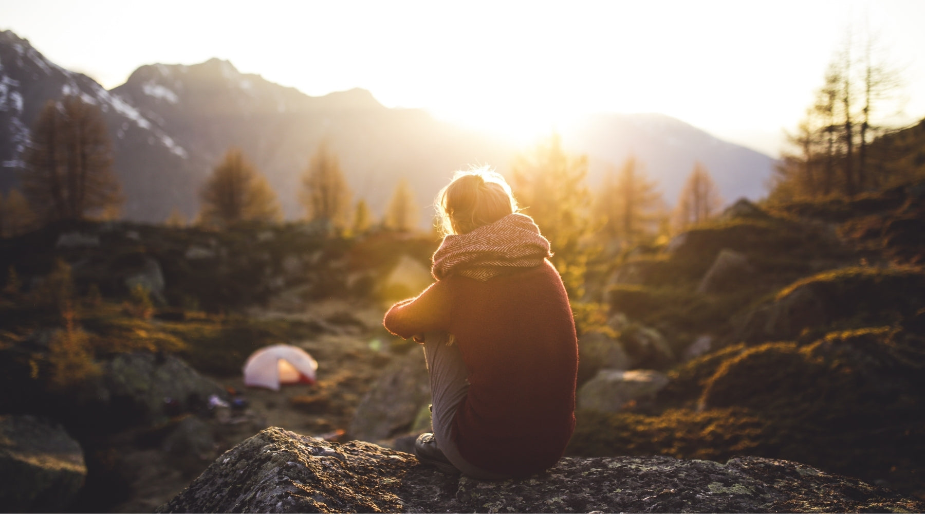 Jeune femme face à un coucher de soleil et sa tente 1 place dans une vallée