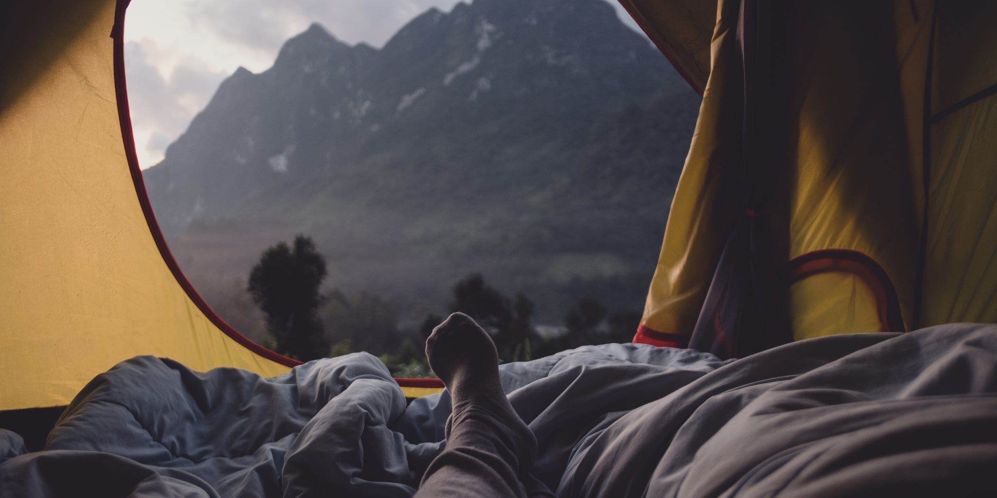 Campeur allongé dans une tente avec vue sur les montagnes - Koksoak Outdoor