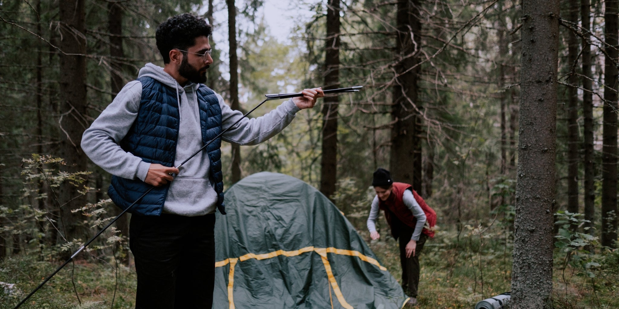 Couple en forêt qui installe une tente 2 places autoportante - Tente autoportée verte pour deux personnes