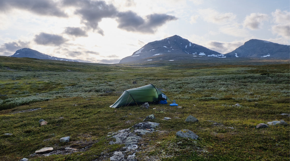 Tente tunnel 2 places verte dans une vallée devant des montagnes rocheuses